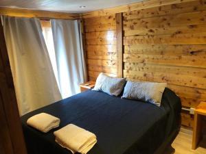 a bedroom with a blue bed with a wooden wall at Molle Alojamiento Serrano in Villa Icho Cruz
