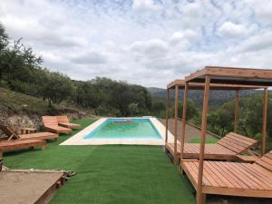 a swimming pool with benches and a gazebo at Molle Alojamiento Serrano in Villa Icho Cruz