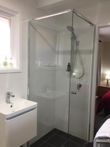 a shower with a glass door next to a sink at Wanderers Retreat in Jindabyne