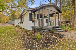 una pequeña casa blanca con porche en un patio en Cozy Home W/ King Bed & Lake access, en Canandaigua