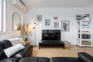 sala de estar con sofá negro y TV en 'Laidback Lygon' A Two-storey Inner-city Oasis, en Melbourne