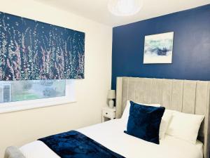 a bedroom with a bed with a blue accent wall at 2BR*Free Parking*Off A12*Family*Contractors in Barkingside