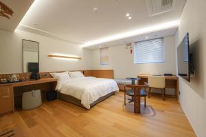 um quarto com uma cama, uma secretária e uma mesa em Hotel Ground27 em Busan