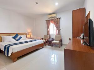 a bedroom with a bed and a television and a desk at Ruby Star Hotel- Near Bến Thành Market in Ho Chi Minh City