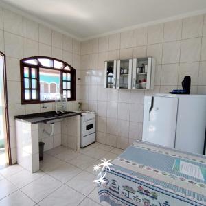a white kitchen with a refrigerator and a window at Apartamento dos Sonhos in Ilha Comprida