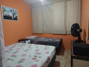 - une chambre avec 2 lits et un ventilateur dans l'établissement Apto em Pitangueiras no Guarujá para temporada, à Guarujá