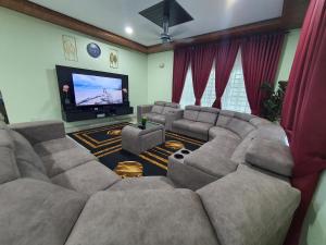 uma sala de estar com um sofá grande e uma televisão de ecrã plano em VILLA SARA PRIVATE POOL ALOR SETAR em Langgar