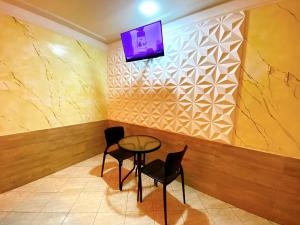 a table and chairs in a room with a tv on a wall at Motel Ceki Sabe in Natal