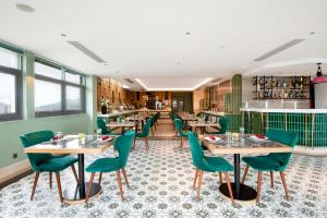 a restaurant with tables and green chairs at Hadana Boutique Hotel in Da Nang
