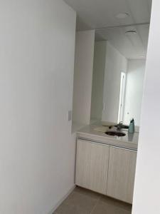 a white kitchen with a sink and a mirror at Departamento tornquist por día in Tornquist +3 photos