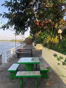 a picnic table and benches next to the water at Ruen Thai Ban Rim Nam in Kamphaeng Phet