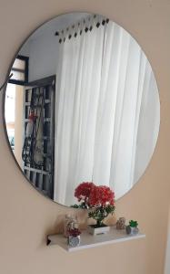 a mirror on a wall with a shelf with flowers at acogedora casa Rochi in Guaduas