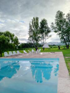 een zwembad met stoelen en een tent en bomen bij La Posada de los Vallistos - Casa de Campo en El Mollar Chicoana 
