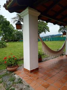 een veranda met een hangmat en een grasveld bij La Posada de los Vallistos - Casa de Campo en El Mollar Chicoana 