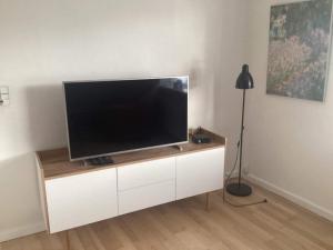 telewizor z płaskim ekranem siedzący na białej szafce w obiekcie Holiday home Nykøbing F 