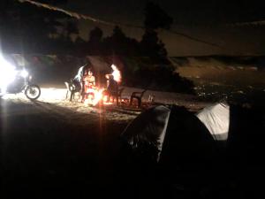 un grupo de personas sentadas alrededor de un campamento de fuego por la noche en Free style camps, en Mussoorie