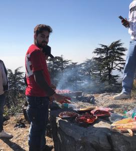 a man standing next to a grill with meat at Free style camps in Mussoorie