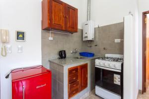 a small kitchen with a stove and a red refrigerator at Departamentos Valle Azul in Santa Rosa de Calamuchita