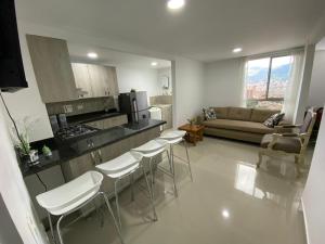 uma cozinha e sala de estar com sofá e cadeiras em Frontera em Itagüí