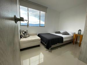 um quarto com uma cama, um sofá e uma janela em Frontera em Itagüí
