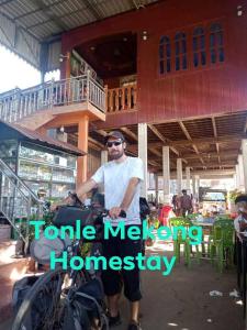 mężczyzna jeżdżący motocyklem przed domem w obiekcie Tonle Mekong Homestay w mieście Krong Kracheh