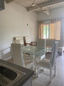 Un comedor con una mesa de cristal y sillas blancas. en Cabañas Paulamar - Apto 2 - Tolu, en La Gloria