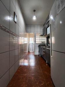 a kitchen with white tile walls and a long hallway at Casa Aeroporto Guarulhos até 8 pessoas com WIFI in Guarulhos