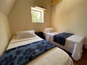 two beds in a room with a window at Chez Humbert in Santiago
