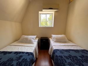 two beds in a small room with a window at Chez Humbert in Santiago