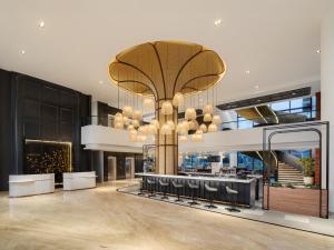 a lobby with a large chandelier in a building at Luminor Hotel Padjadjaran Bogor by WH in Bogor