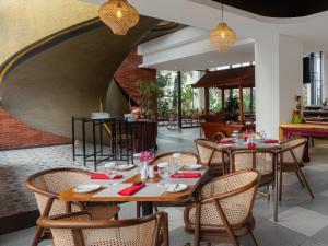 een restaurant met tafels en stoelen en een bakstenen muur bij Luminor Hotel Padjadjaran Bogor by WH in Bogor