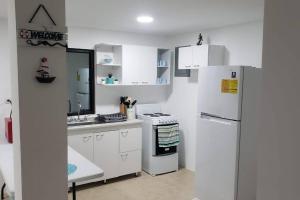 a kitchen with white cabinets and a white refrigerator at Primera Casa de Contenedores en Monterrico. in Monterrico