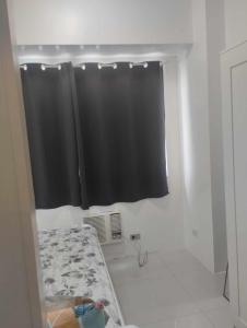 uma casa de banho com uma cortina de chuveiro preta e um berço em Staycation at moa em Manila