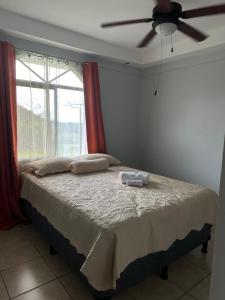 sypialnia z łóżkiem z wentylatorem sufitowym i oknem w obiekcie Hermosa casa para descanso w mieście Linda Vista
