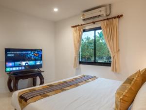 a bedroom with a bed and a flat screen tv at Isara Nai Yang resort in Nai Yang Beach