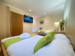 1 dormitorio con 2 camas y TV en la pared en Lake District cottage in 1 acre gardens off M6 en Penrith