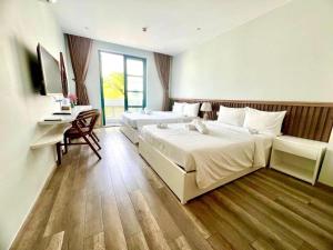 um quarto de hotel com duas camas e uma secretária em Larosa Hotel em Phu Quoc