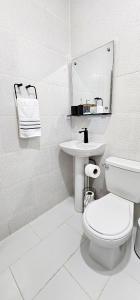 a white bathroom with a toilet and a sink at Rincón Marino in Sosúa