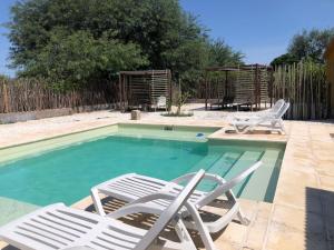 a swimming pool with two lawn chairs and a table at LAS SALINAS GRAN HOTEL in San José de las Salinas