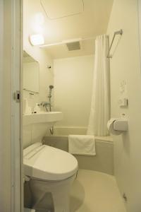 a white bathroom with a toilet and a sink at Domo Hotel in Tokyo