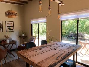 - une grande table en bois dans le salon avec fenêtres dans l'établissement Casa Maqui, à Talca