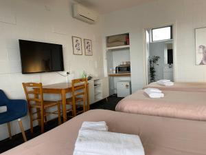 een kamer met 2 bedden, een tafel en een televisie bij Kilcunda Ocean View Motel in Kilcunda