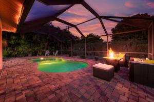 Villa Harmony -Tropical Villa Retreat with private pool in desirable South West Cape Coral في كيب كورال: فناء مع مسبح وطاولة ومدفأة