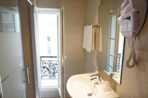 een badkamer met een wastafel, een spiegel en een douche bij Hotel Zora in Parijs