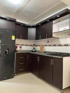 una cucina con armadi marroni e frigorifero nero di La Casa de Ian a Santa Marta