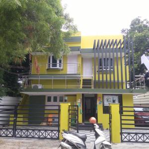 een geel gebouw met een scooter ervoor geparkeerd bij gplushomestay in Madurai