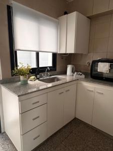 eine Küche mit weißen Schränken und einer Spüle und einer Mikrowelle in der Unterkunft Departamento de Josefina in Santiago del Estero