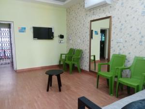 een wachtkamer met groene stoelen en een spiegel bij gplushomestay in Madurai