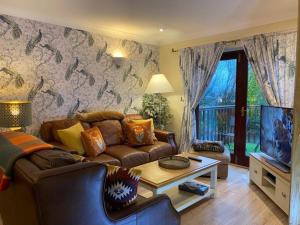 een woonkamer met een bank en een tv bij Lake District cottage in 1 acre gardens off M6 in Penrith