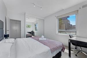 a white bedroom with a bed and a sink at Ocean View 1 bedroom Private Apartment next to Maroubra Beach in Sydney